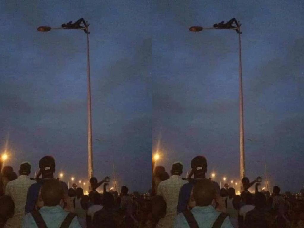 Photos: Thief Climbs And Relaxes On A Streetlight Pole To Avoid Beatings